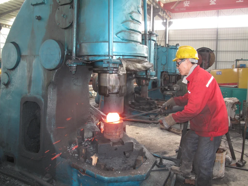 Operator forging a heated steel grinding ball